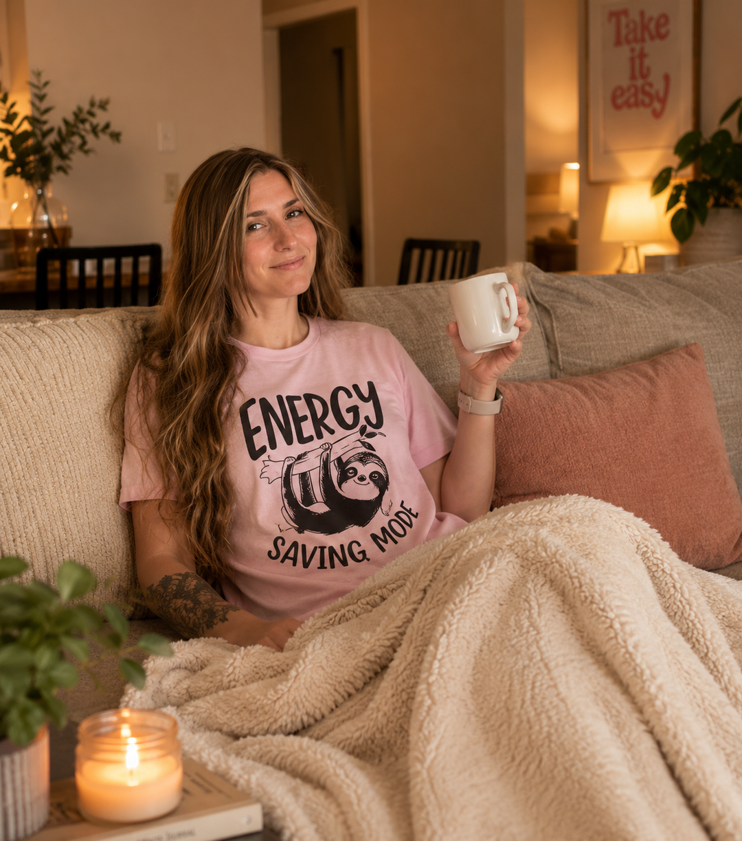Woman sitting on a couch holding a mug, wearing a 'Energy Saving More' shirt, with a cozy atmosphere.
