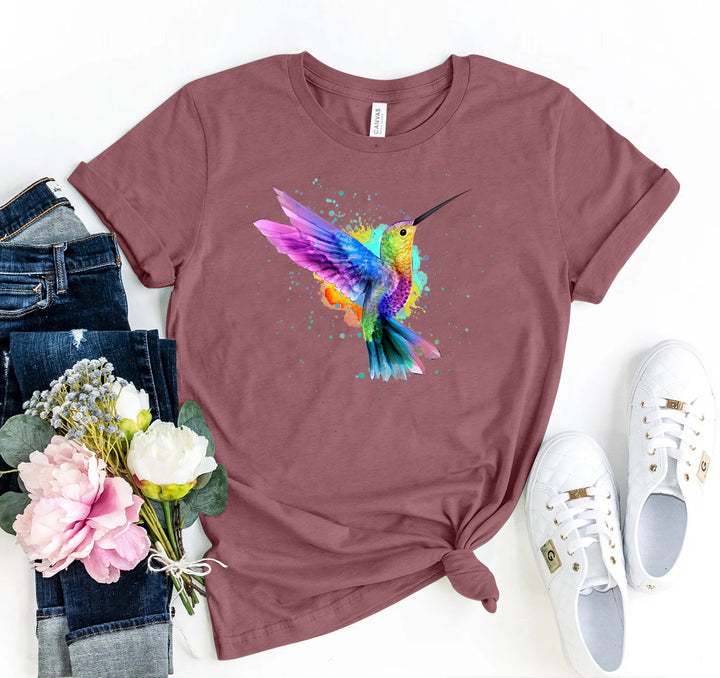 Mauve t-shirt with colorful hummingbird design, jeans, sneakers, and flowers